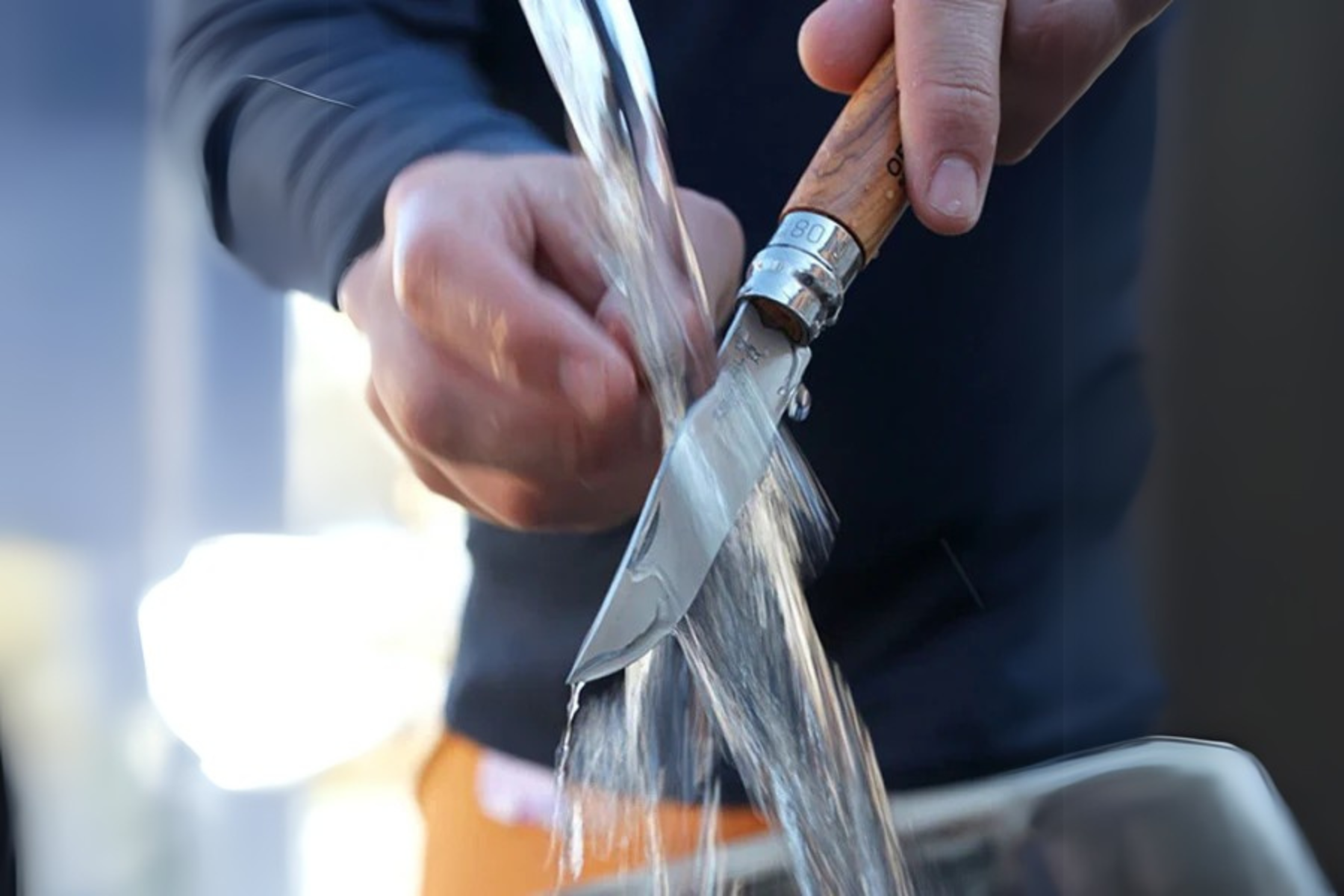 persona che lava coltello opinel sotto l'acqua