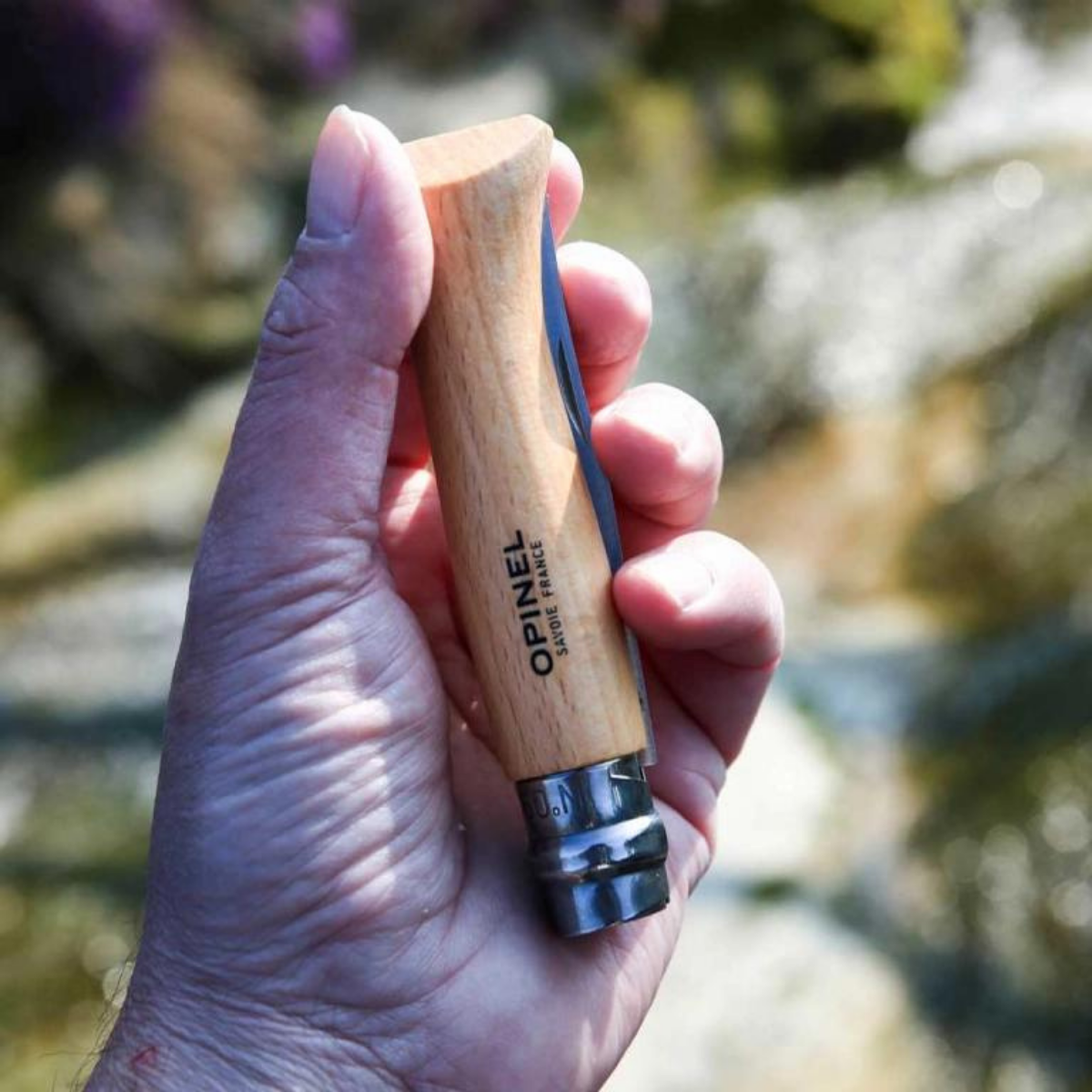 coltello opinel tradional in acciaio inox mostrato chiuso nella mano di una persona 